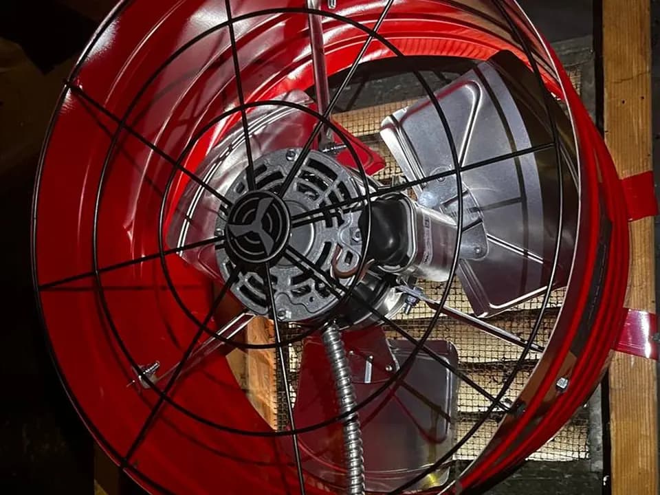 Red whole house fan installed in an attic