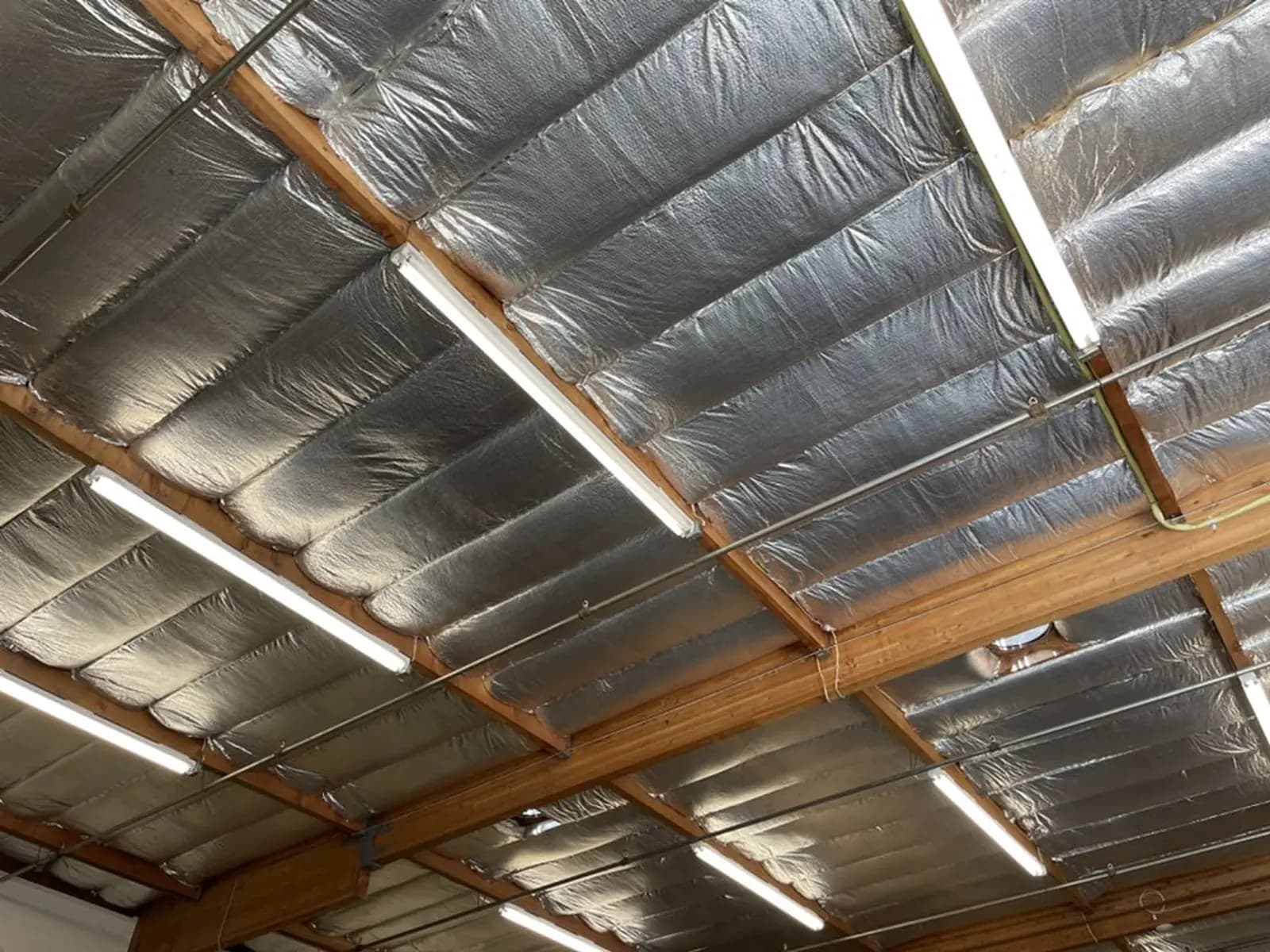 Reflective radiant barrier insulation stapled between the rafters of a ceiling